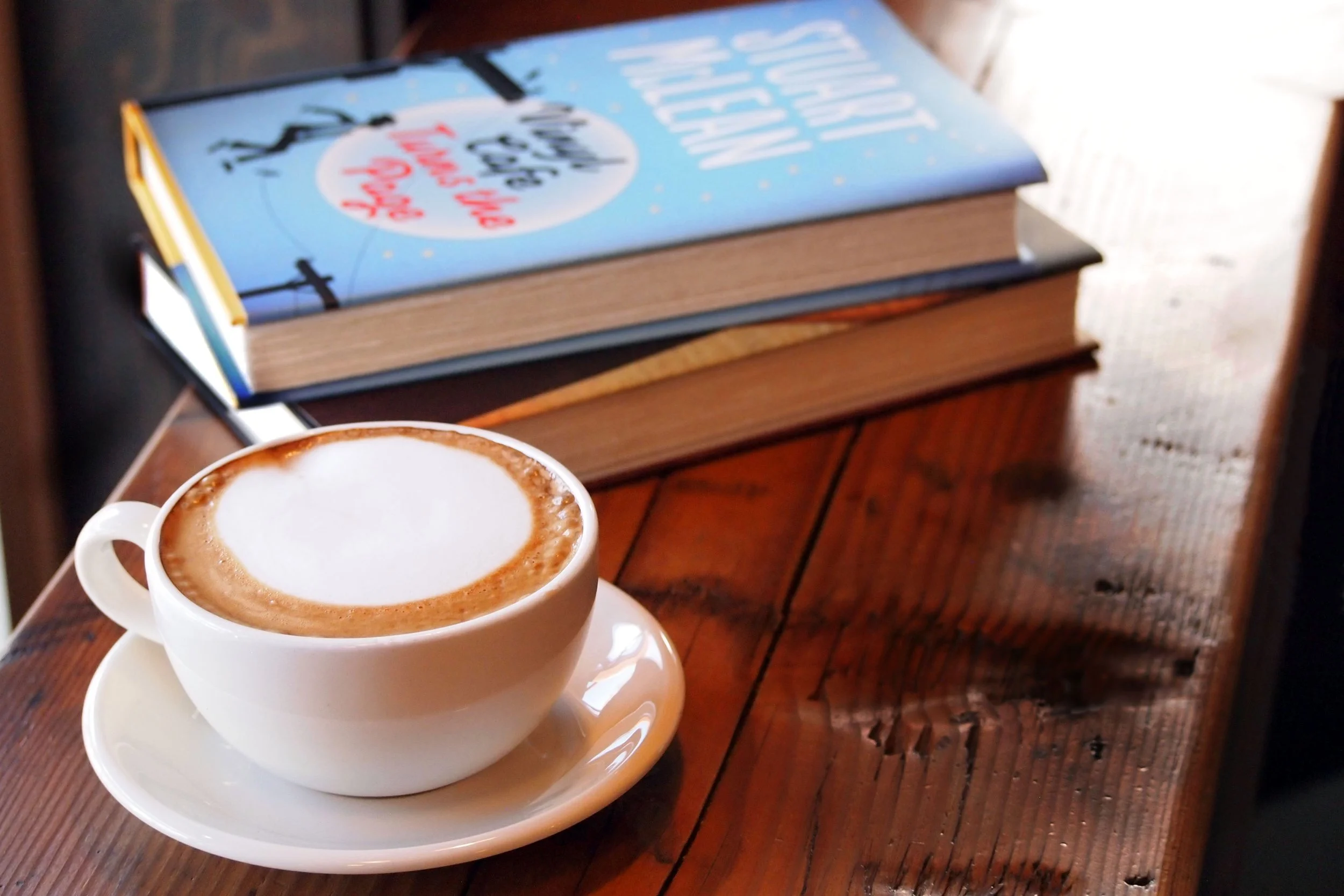 A cup of coffee next to two books